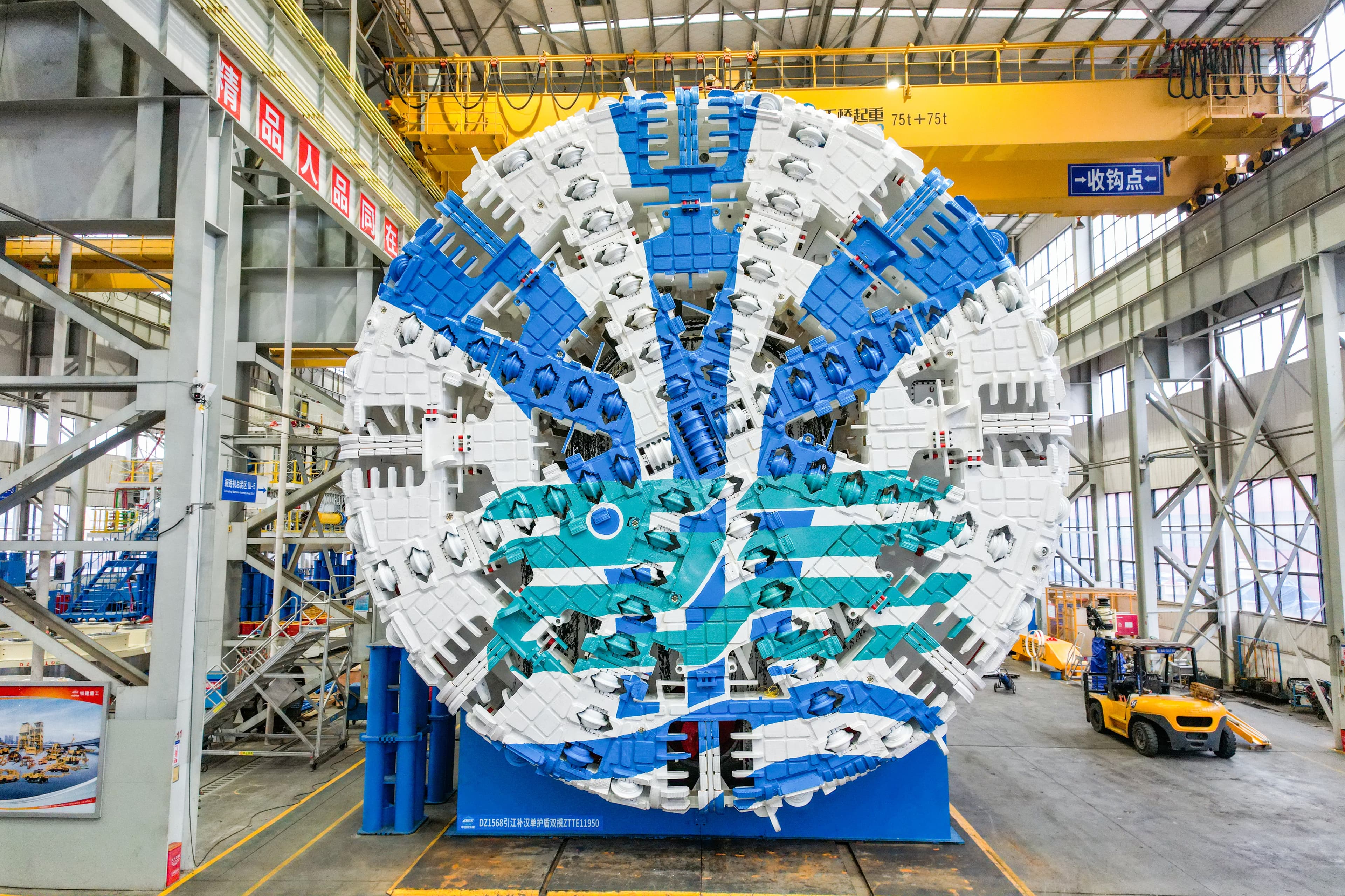 Close-up of the blue and white Jianghan Long'an dual-mode TBM cutterhead showing the radial spoke pattern and disc-cutter mountings on the factory floor